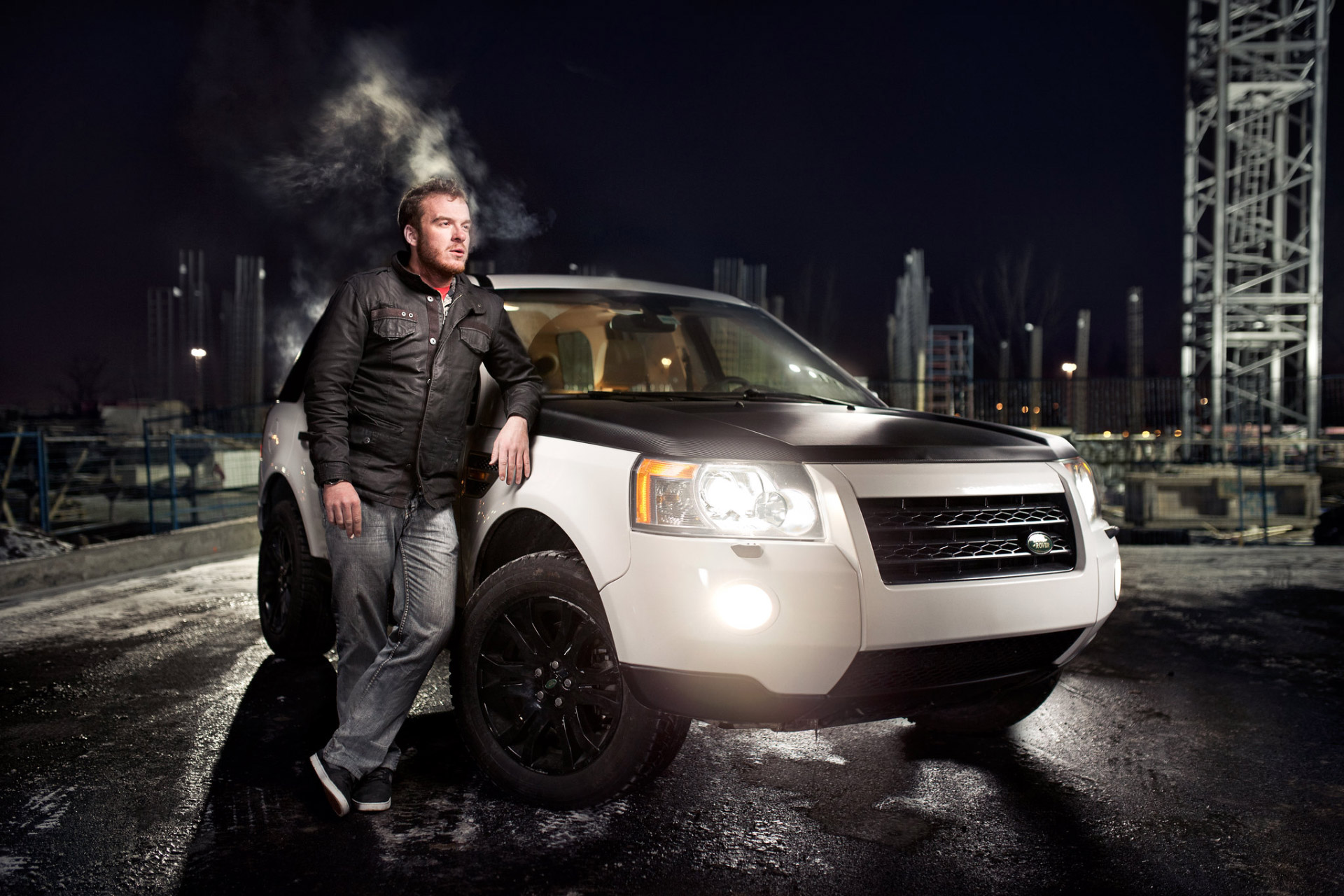 man smoking cigarette with his suv at night